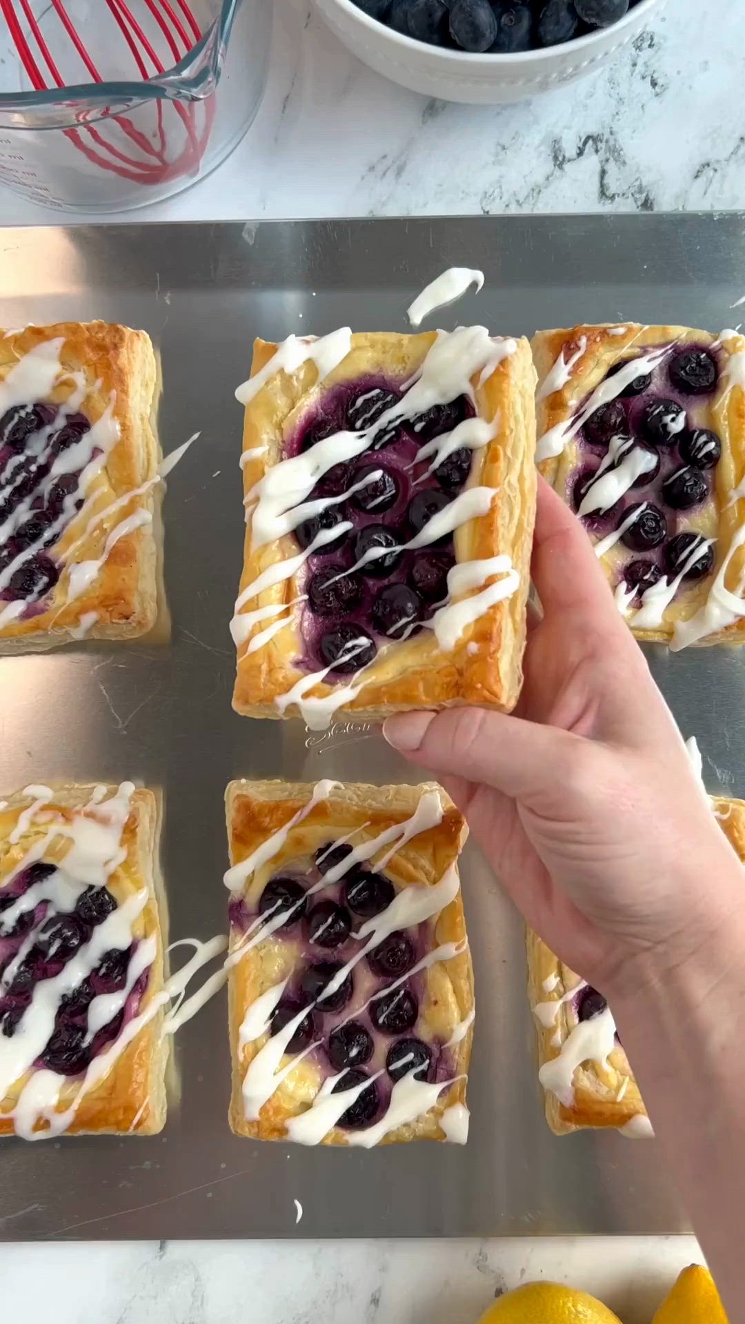 This may contain: a person is placing blueberry cheesecakes on top of each other with icing