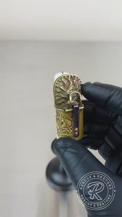 This may contain: a hand holding a gold ring with an ornate design on it