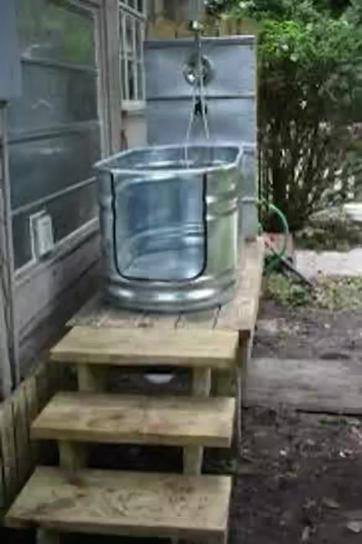 This may contain: a metal bucket sitting on top of wooden steps