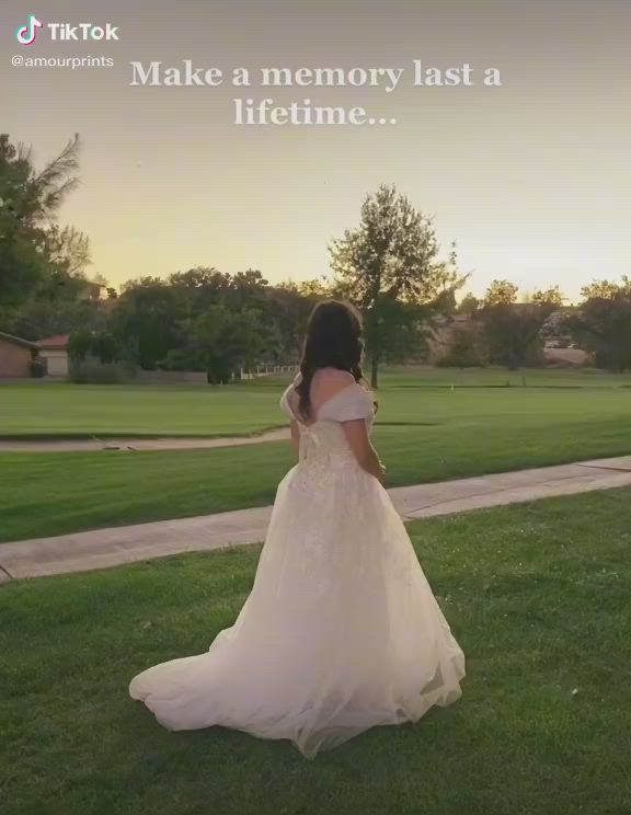 This may contain: a woman in a wedding dress is standing on the grass with her back to the camera