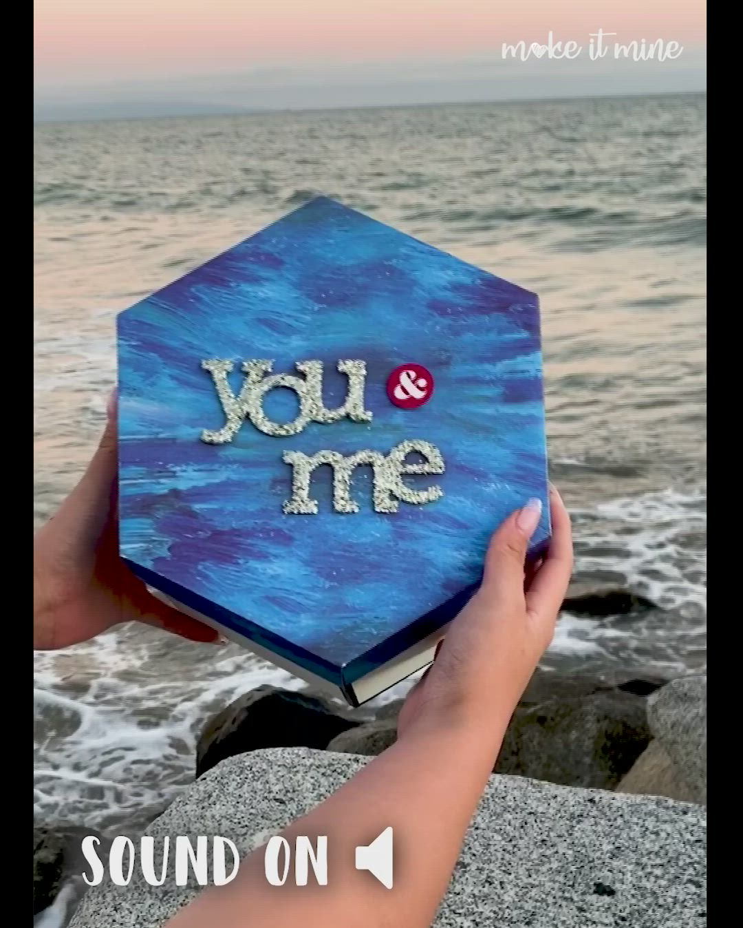 This may contain: someone holding up a book with the words you and me on it in front of water