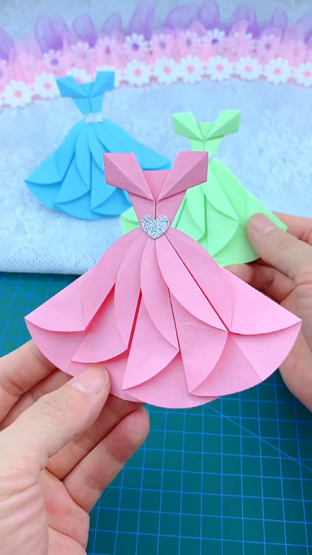 This may contain: someone is holding an origami dress in their hand