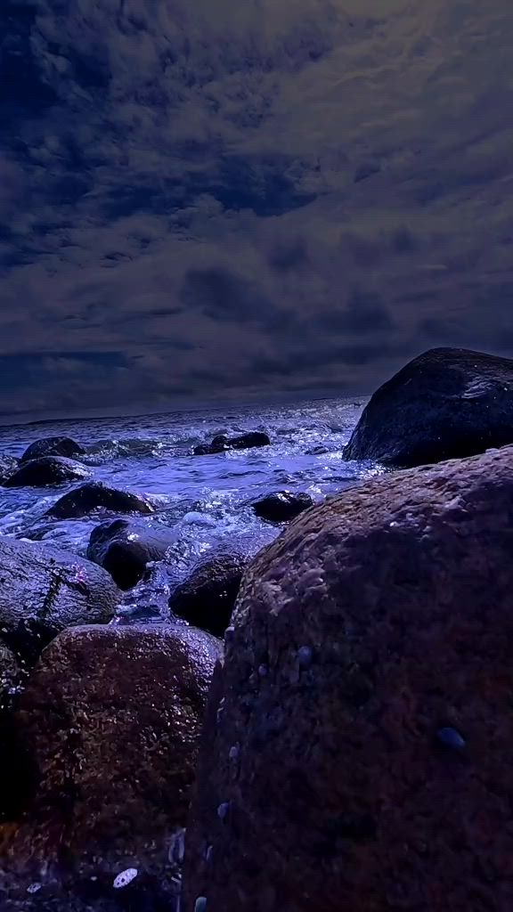 This may contain: the moon shines brightly over some rocks and water