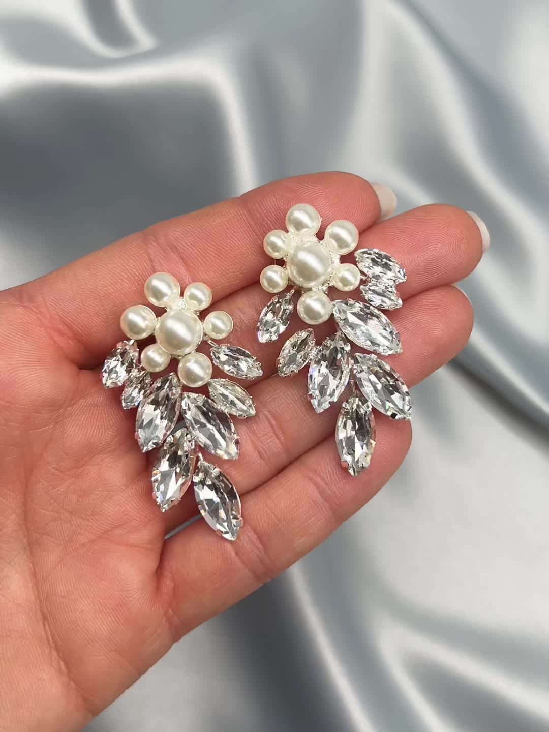 Head turning, bold & floral, our Verona Earrings are the perfect way to make a statement. Add a touch of sophistication and sparkle when you wear these earrings for weddings, black tie events or even your next girls night out. Details: Multiple sized, light ivory pearls look like a flower. Top grade rhinestones for high shine (day or night). Specifications: 2" in length x 1.25" wide. Earrings are slightly heavier than some, but worth it! Tarnish Resistant: Earrings are tarnish resistant for long