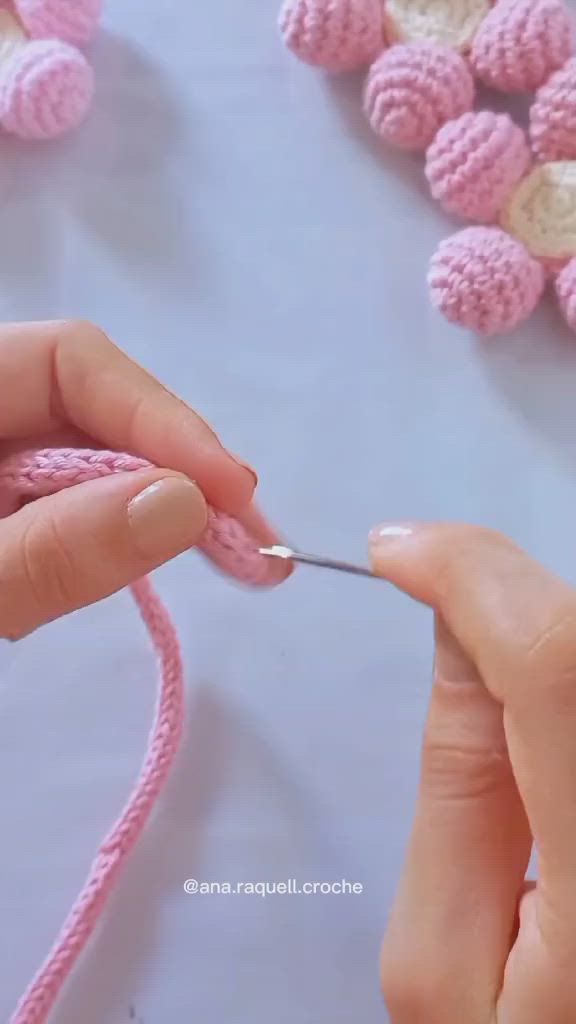 This may contain: someone is crocheting the letters in pink yarn and then knitting them together to make an ornament