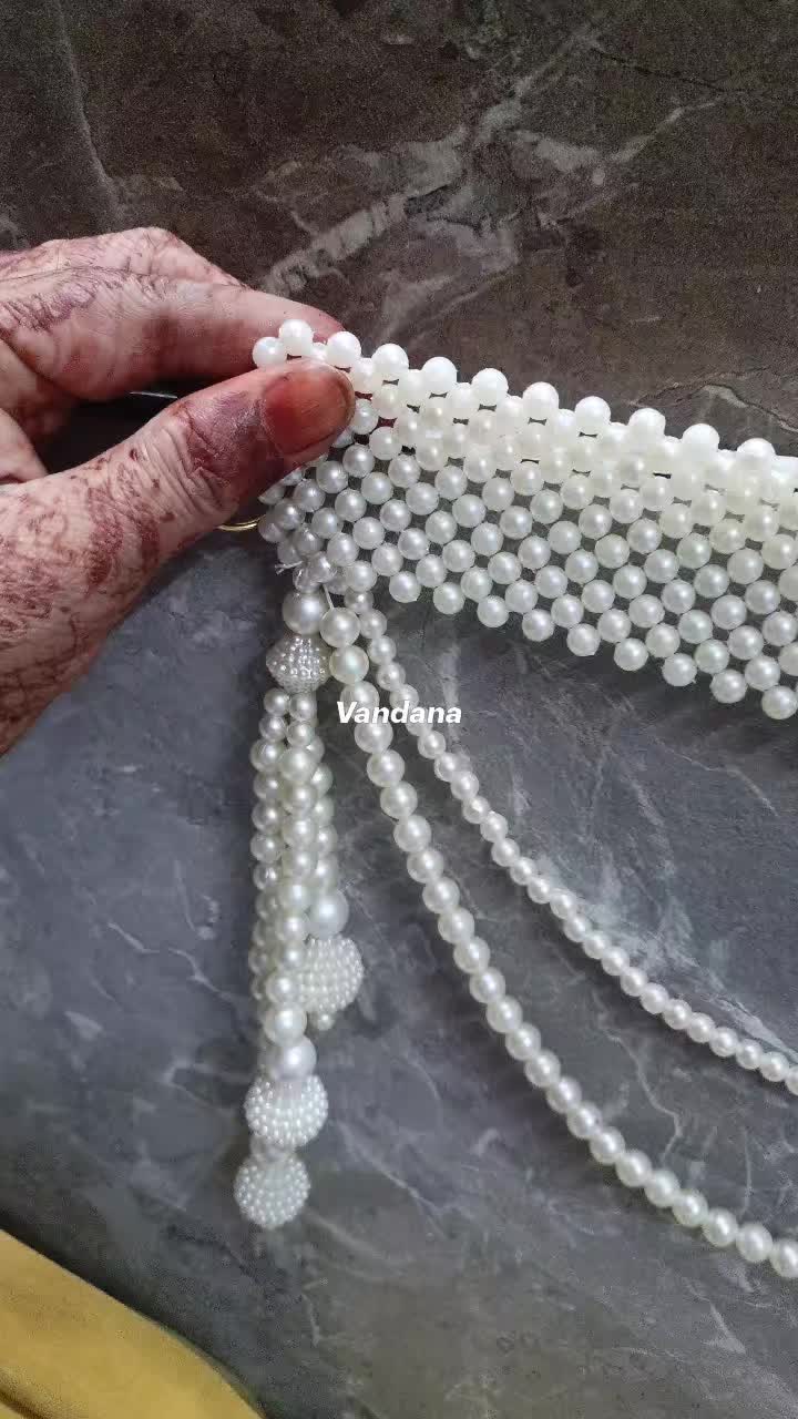 This may contain: a person is holding some beads on their hand and it looks like they are making something out of pearls