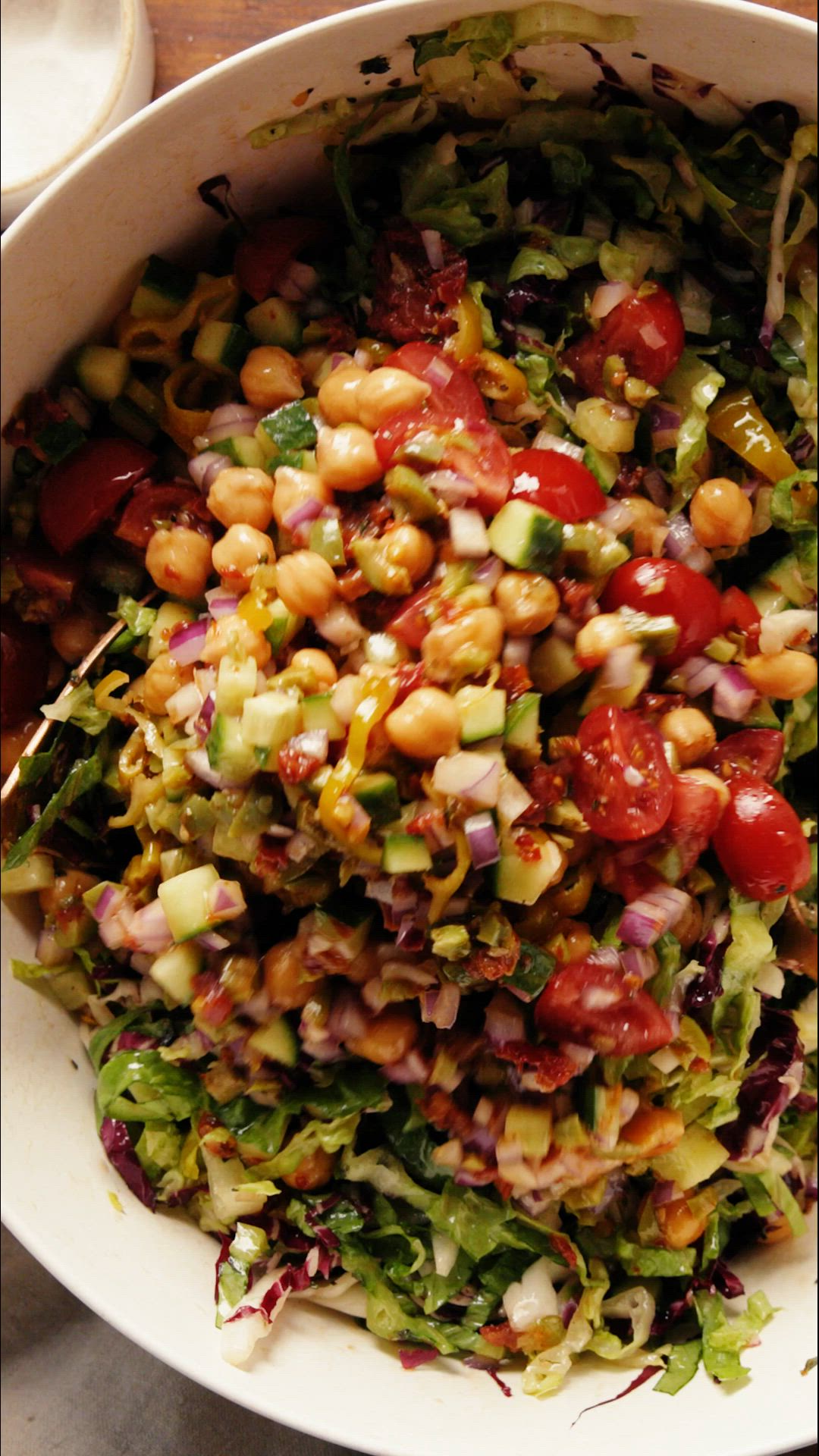 This may contain: a white bowl filled with salad on top of a table