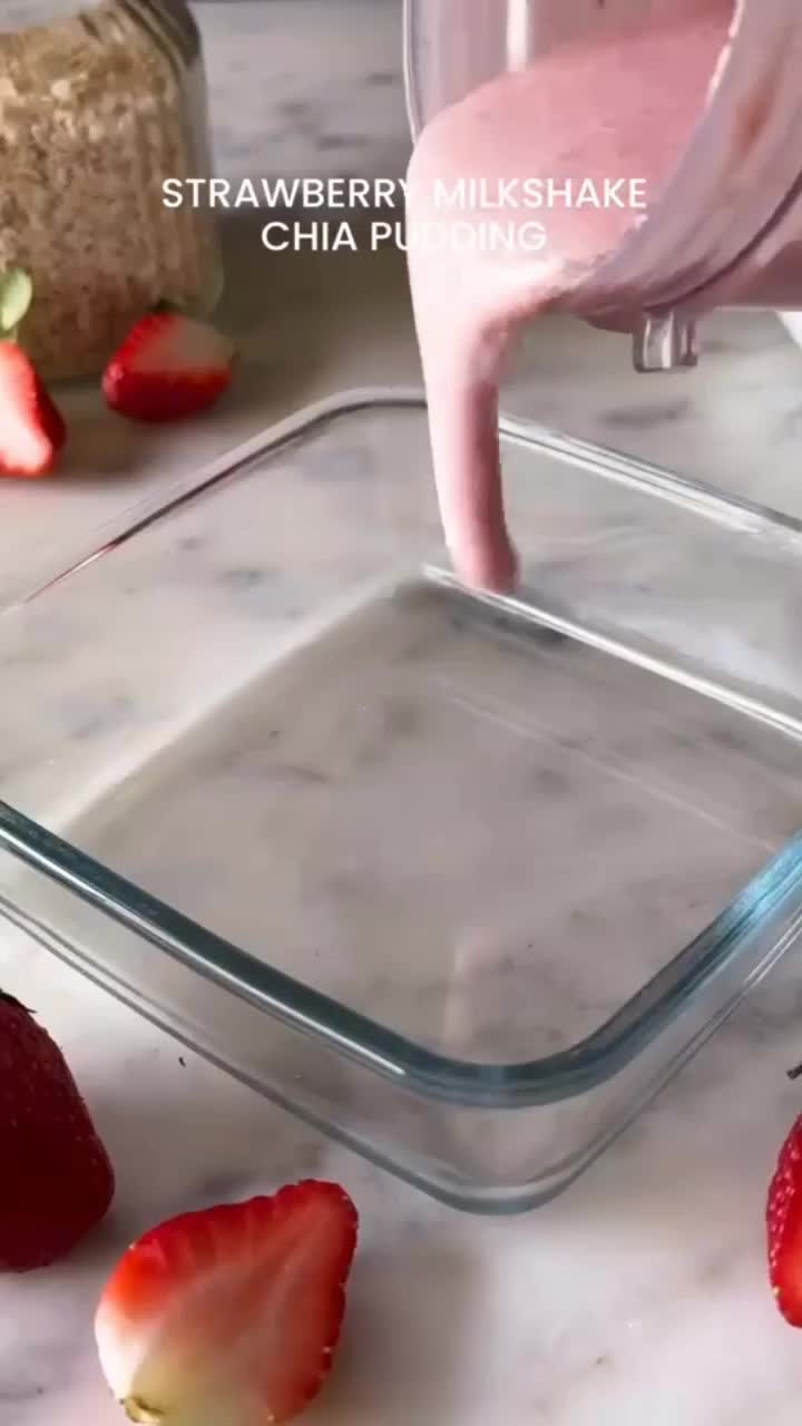 This may contain: strawberries and milk being poured into a glass container on a marble countertop with ingredients for making strawberry milkshake