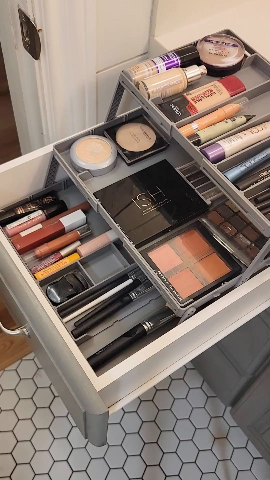 This may contain: an organized makeup drawer in a bathroom