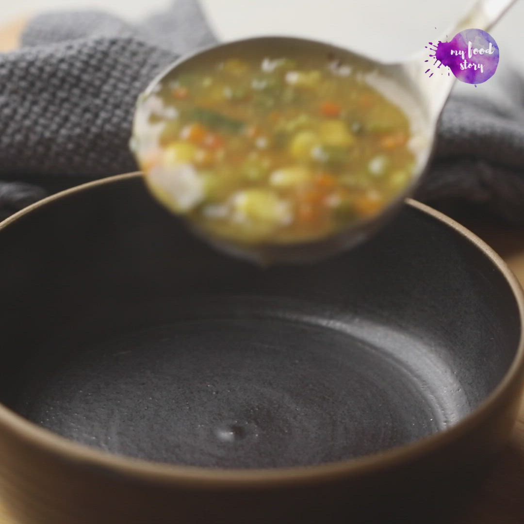 This may contain: a bowl filled with soup sitting on top of a wooden table