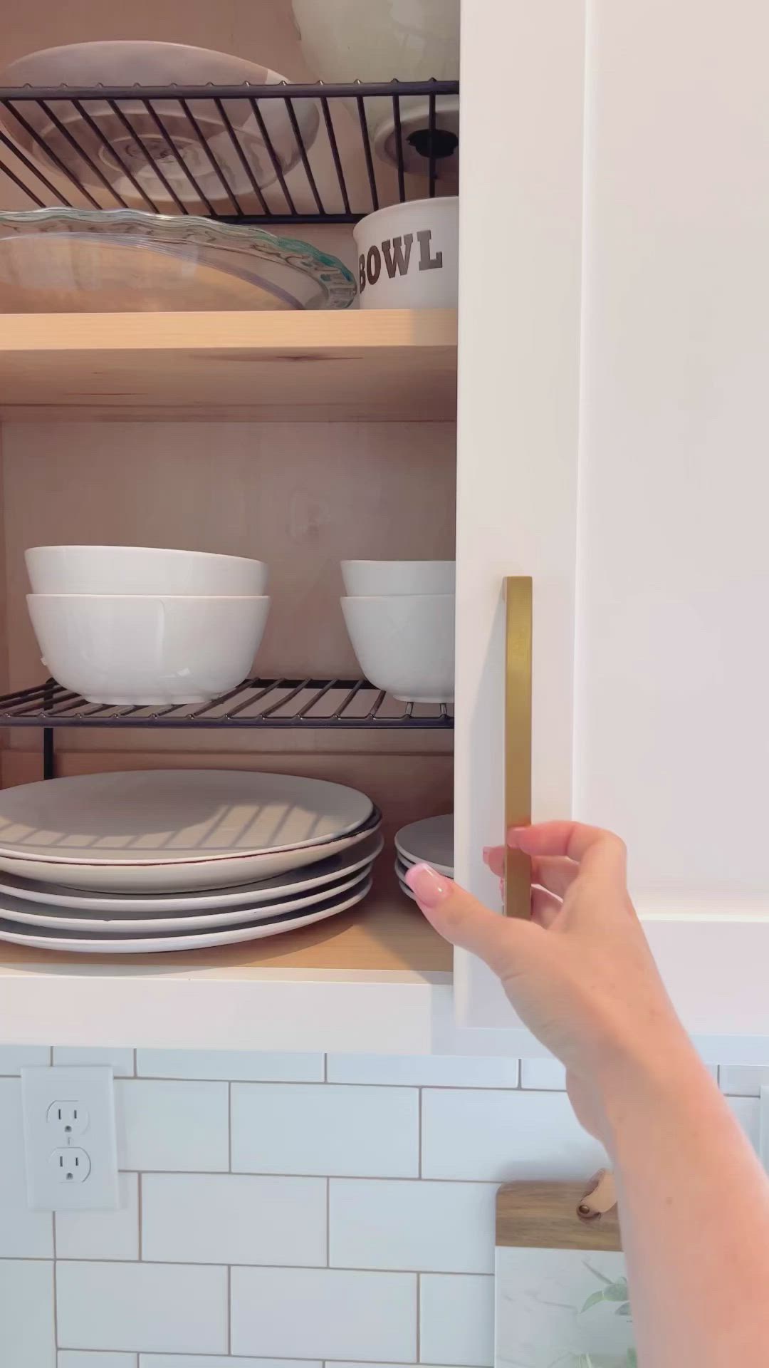 This may contain: a woman is opening the cupboard door to reveal dishes in bowls and plates on the shelves