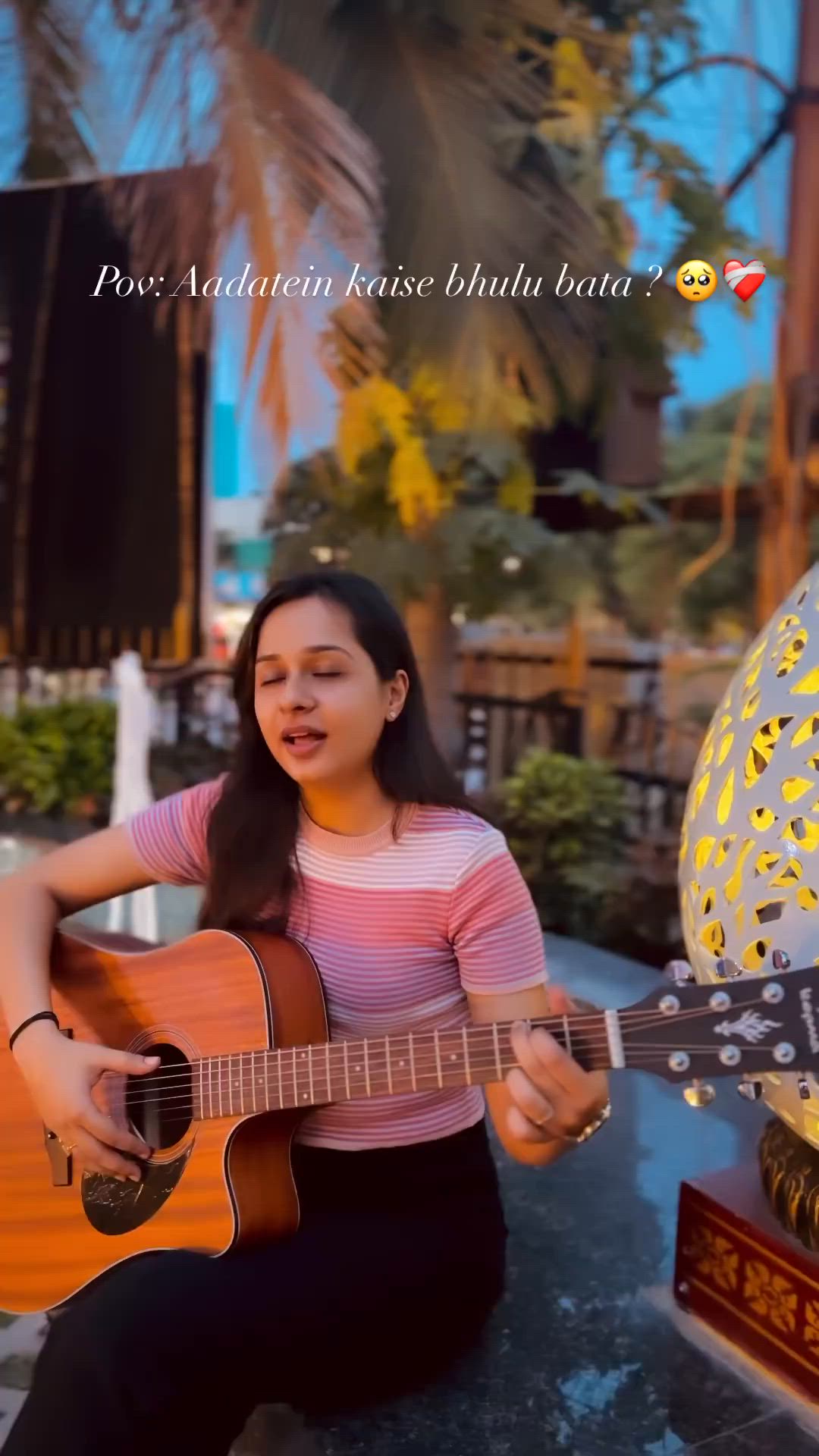 This may contain: a woman sitting on the ground playing a guitar