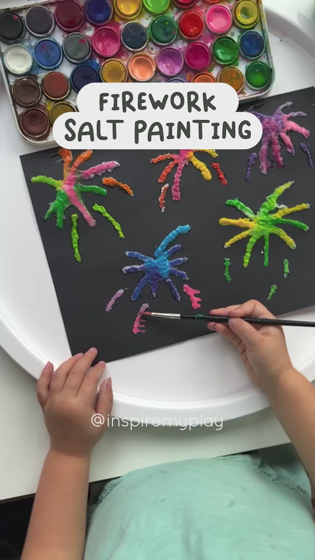 This may contain: a child is painting palm trees on a black paper with watercolors in the background