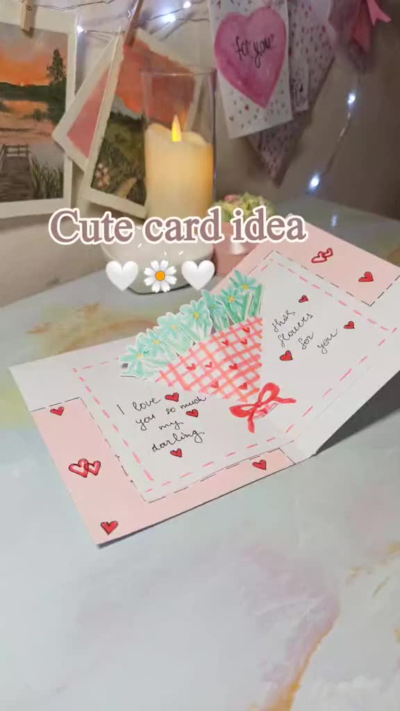 This may contain: two cards with hearts on them sitting on a table next to a candle and some pictures