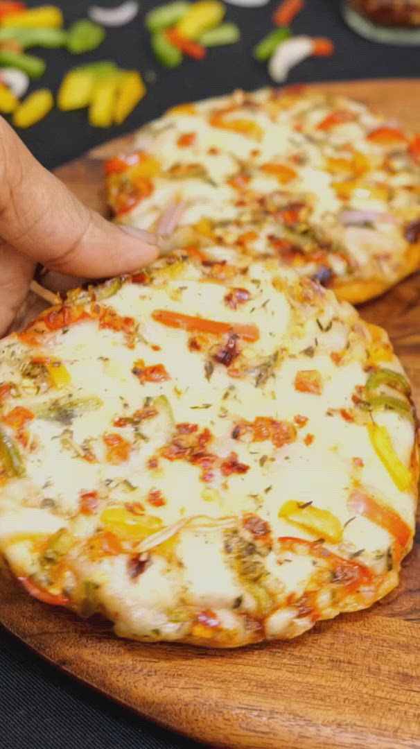 This may contain: two pizzas sitting on top of a wooden cutting board