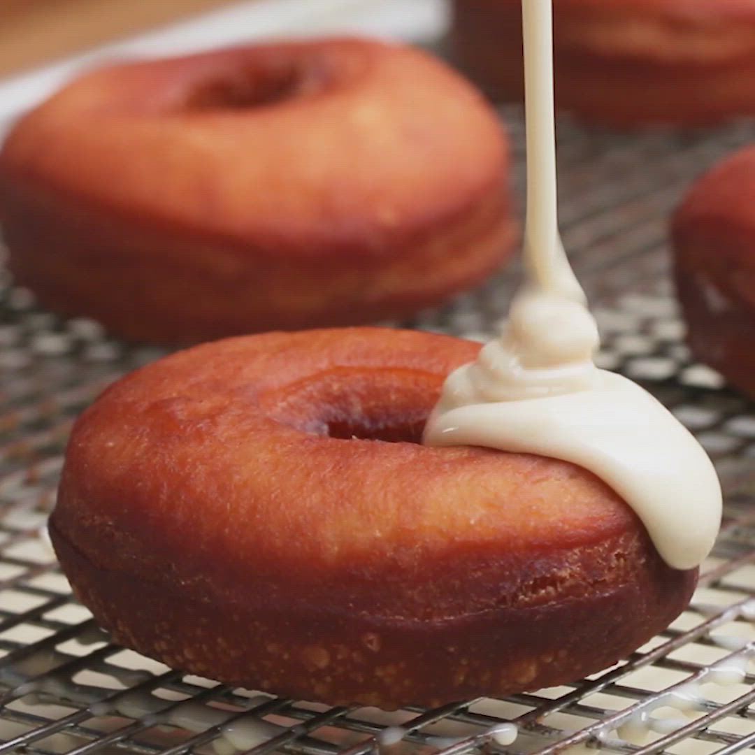 This may contain: donuts are being drizzled with white icing on a cooling rack