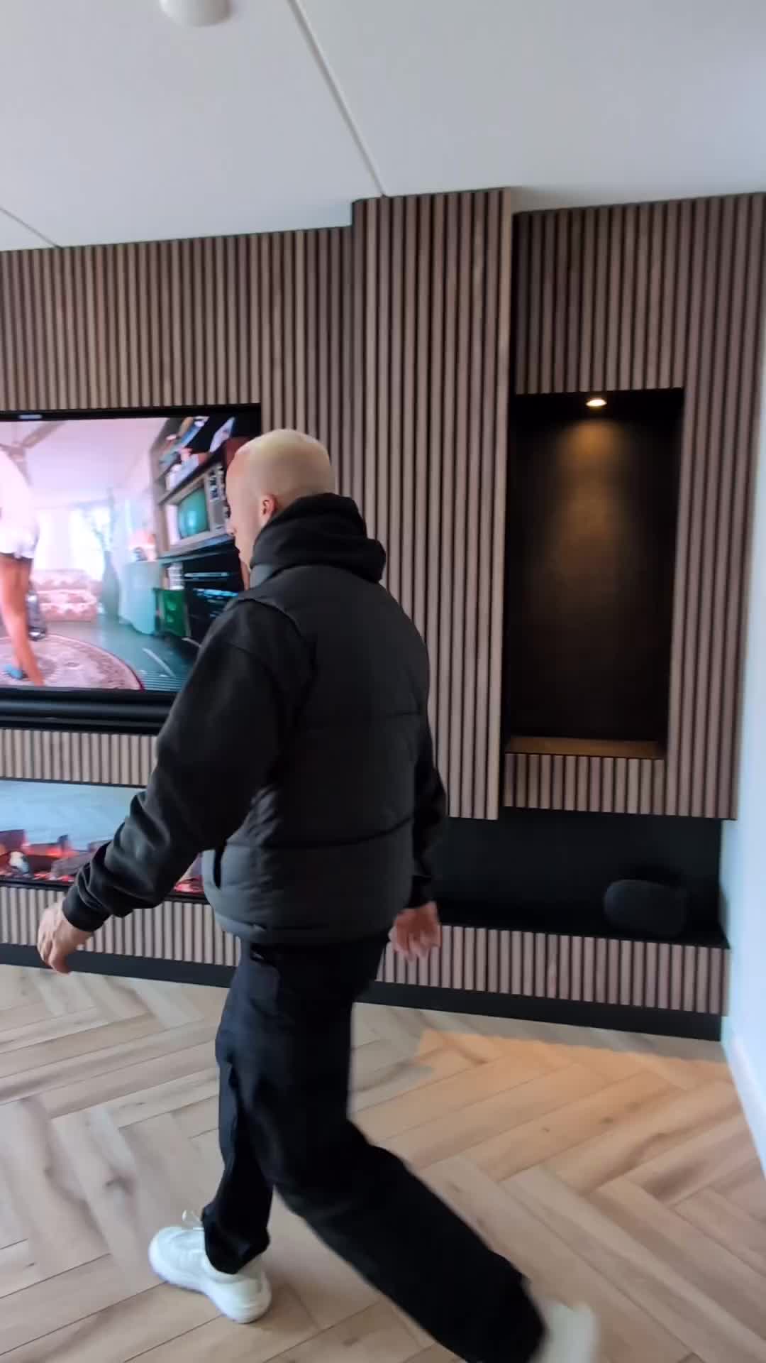 This may contain: a man standing in front of a flat screen tv on top of a wooden floor