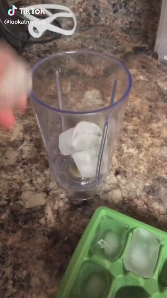 This may contain: ice cubes in a blender on a granite counter top with someone's hand reaching for them