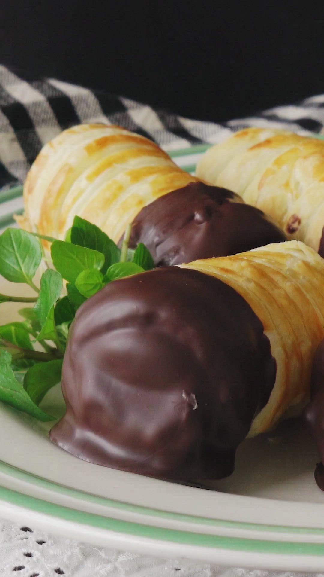 This may contain: chocolate covered croissants on a plate with mint sprigs and leaves