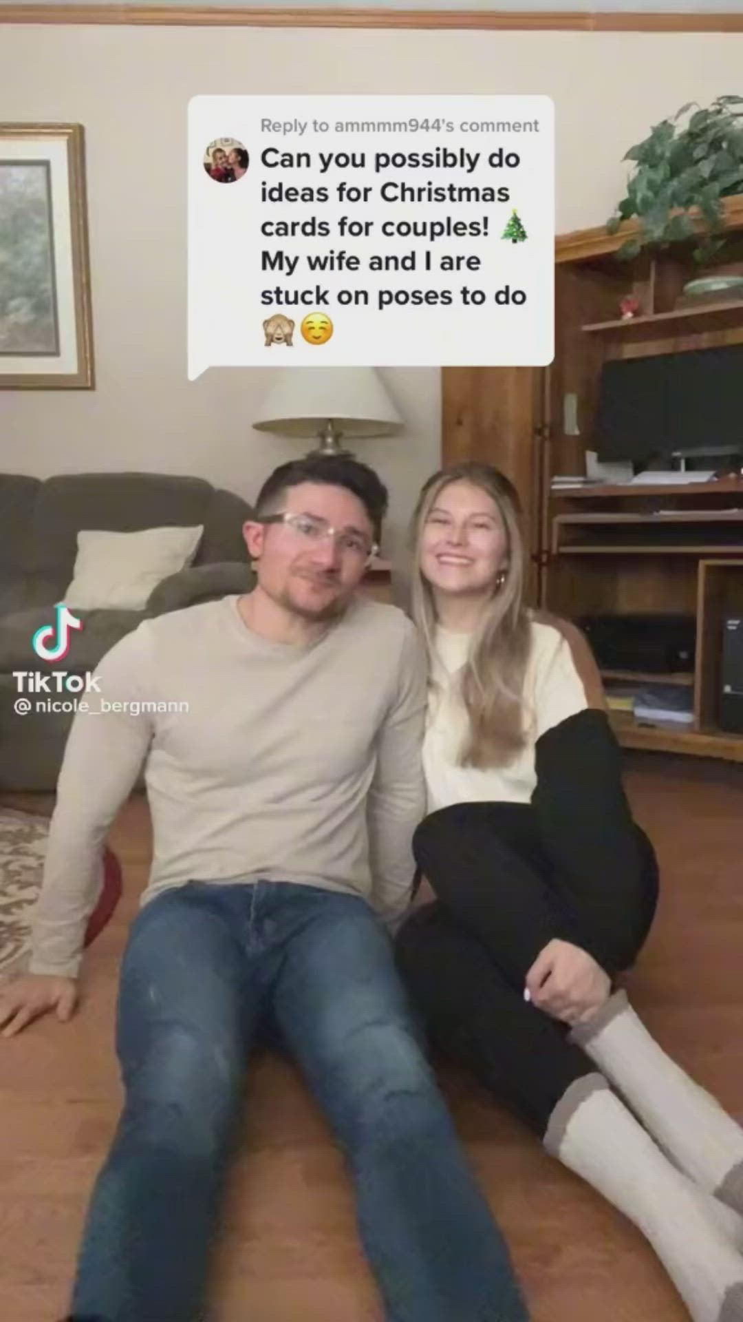 This may contain: a man and woman sitting on the floor in front of a couch with christmas decorations