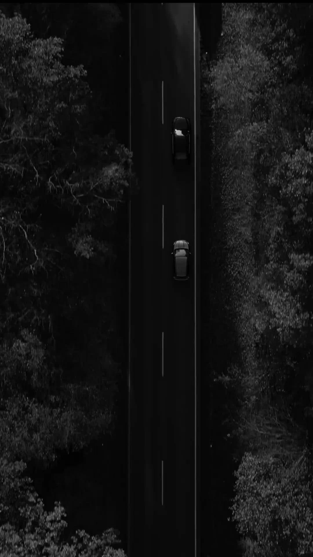 This may contain: an overhead view of a car driving down a road in the woods with trees on both sides