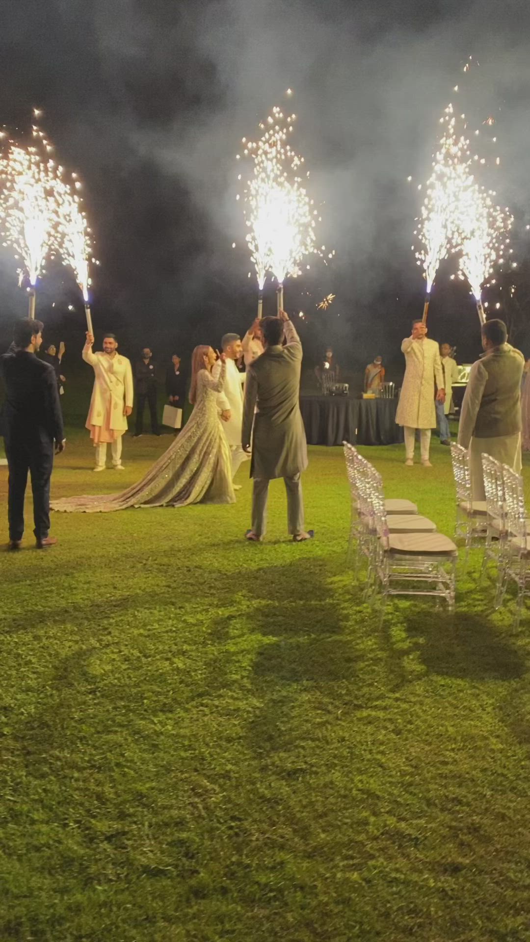 This may contain: the bride and groom are walking down the aisle with their sparklers