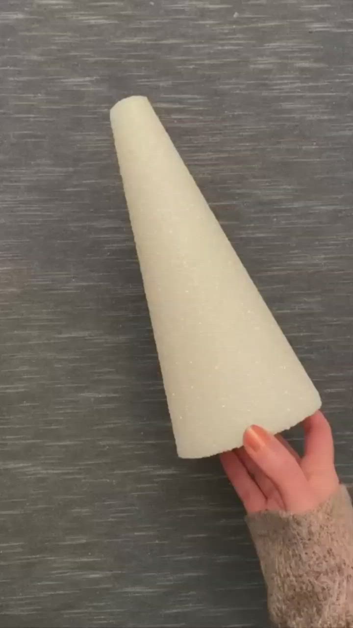 This may contain: a hand holding a white cone on top of a gray surface with the tip pointing towards it