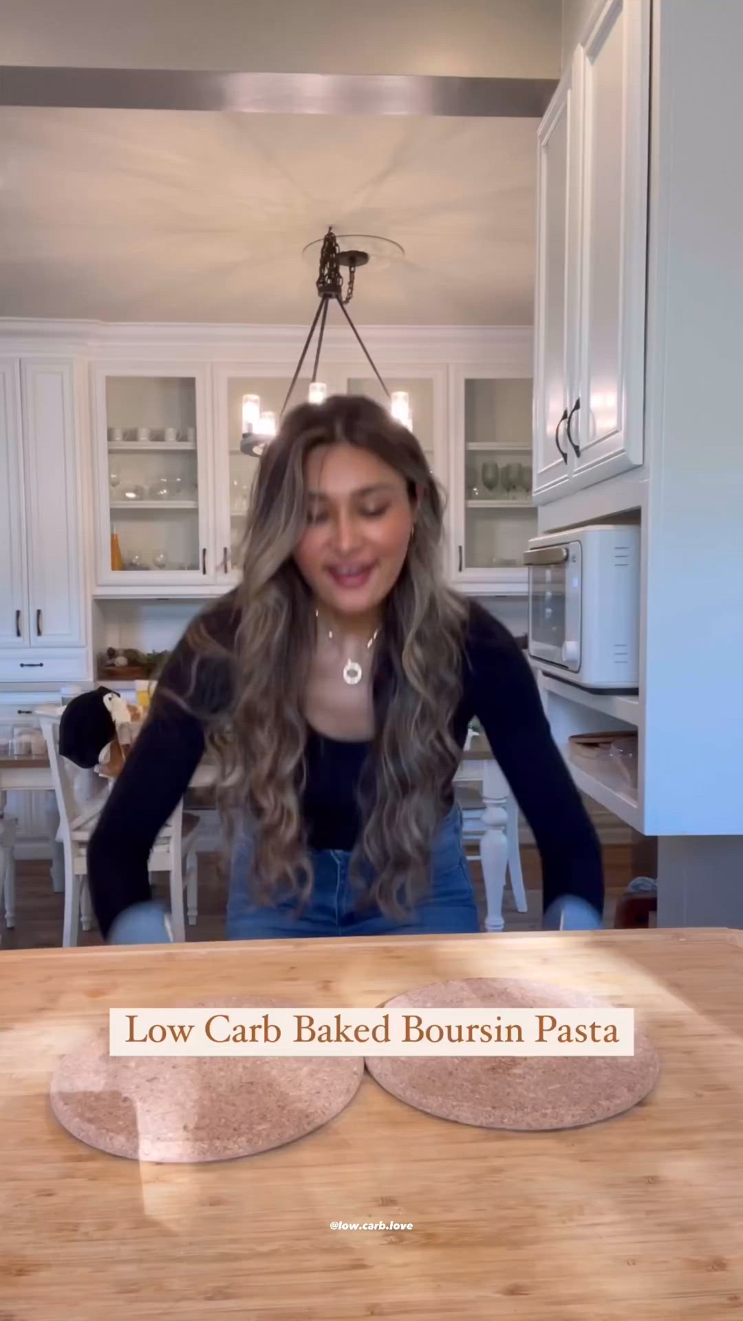 This may contain: a woman standing in front of a pan of food on top of a wooden table