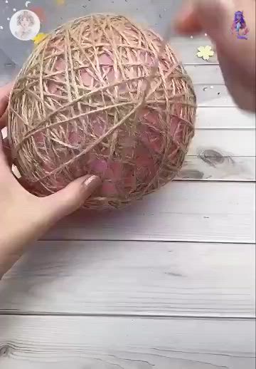 This may contain: someone is holding an object made out of yarn on the table and it looks like a ball