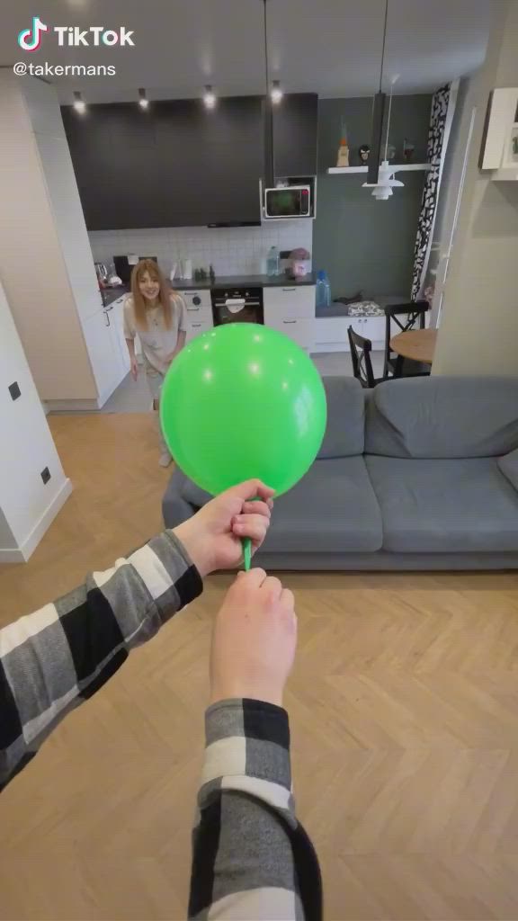 This may contain: a person holding a green balloon in their hand