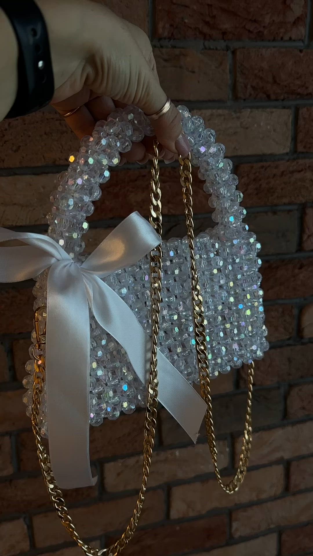 This may contain: a person is holding onto some kind of bag with pearls on it and a white ribbon