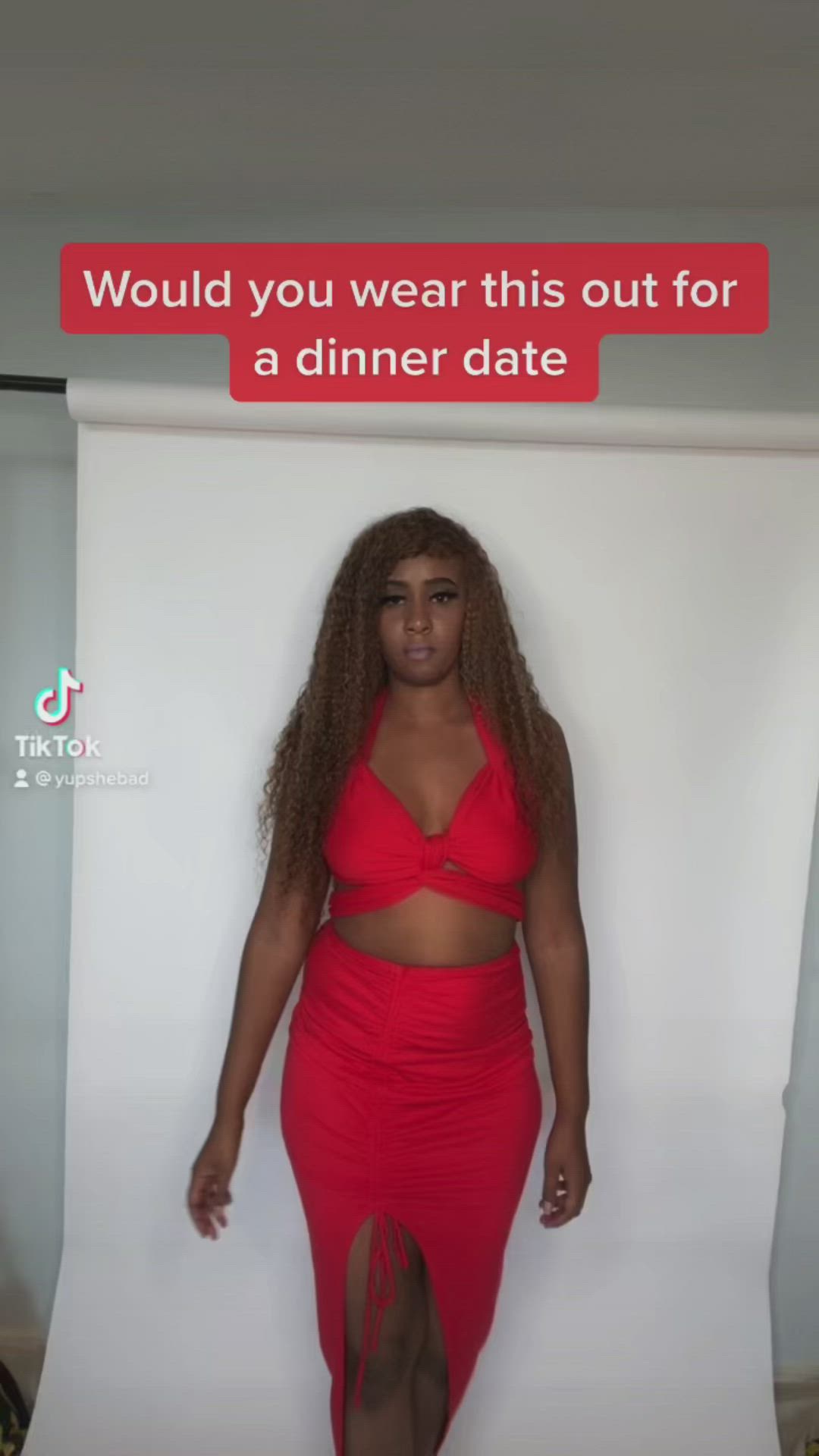 This may contain: a woman in a red dress standing next to a white backdrop with the words would you wear this out for a dinner date?