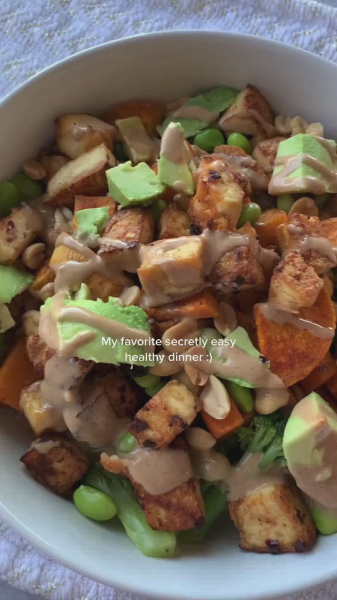 This may contain: a white bowl filled with vegetables covered in dressing