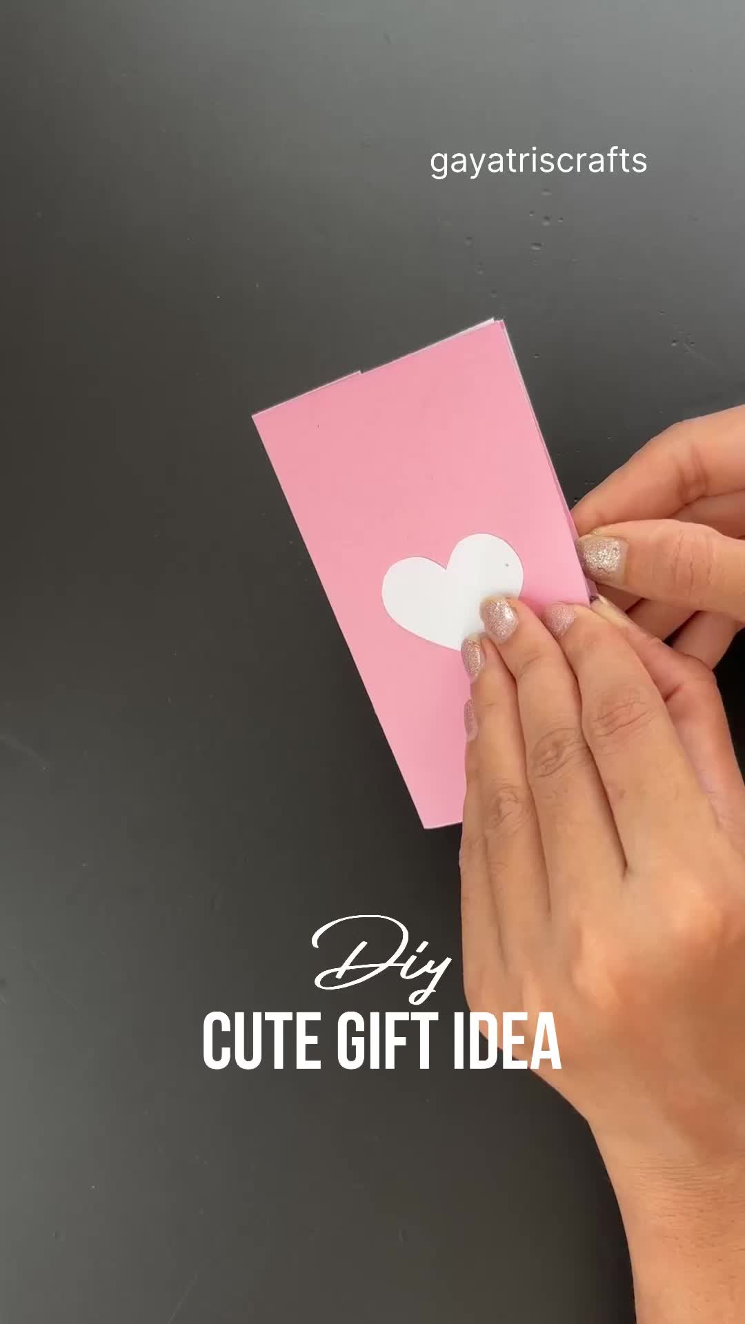 This may contain: a person holding a pink card with a white heart on it and the words diy cute gift idea