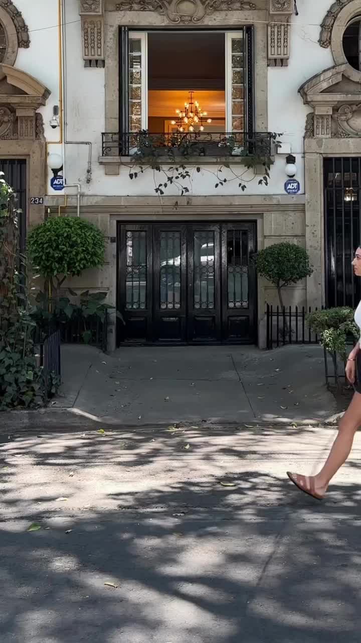 This may contain: a woman walking down the street in front of a building with a sign that reads kco city