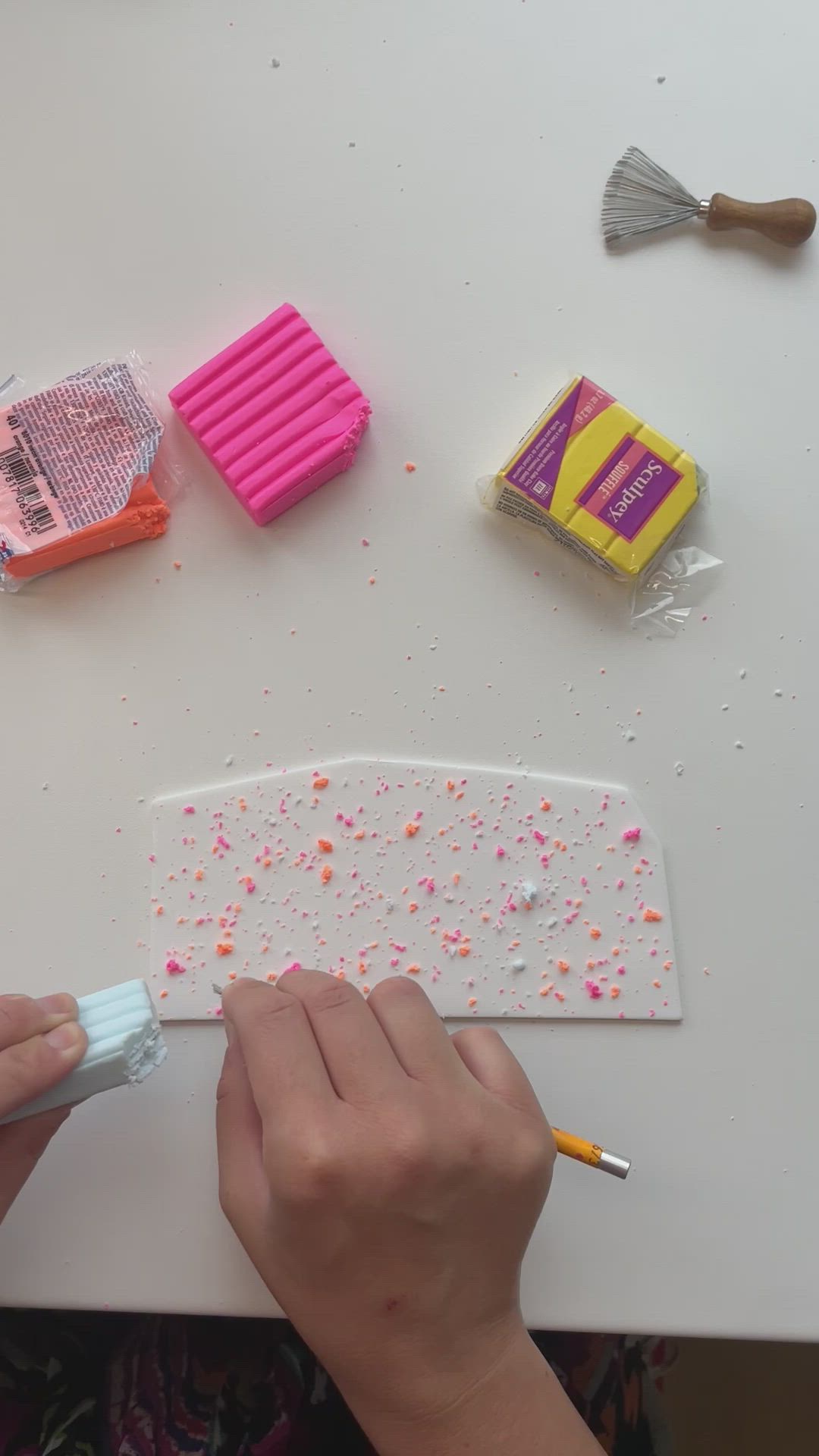 This may contain: a person is painting on a white table with pink and yellow items next to them