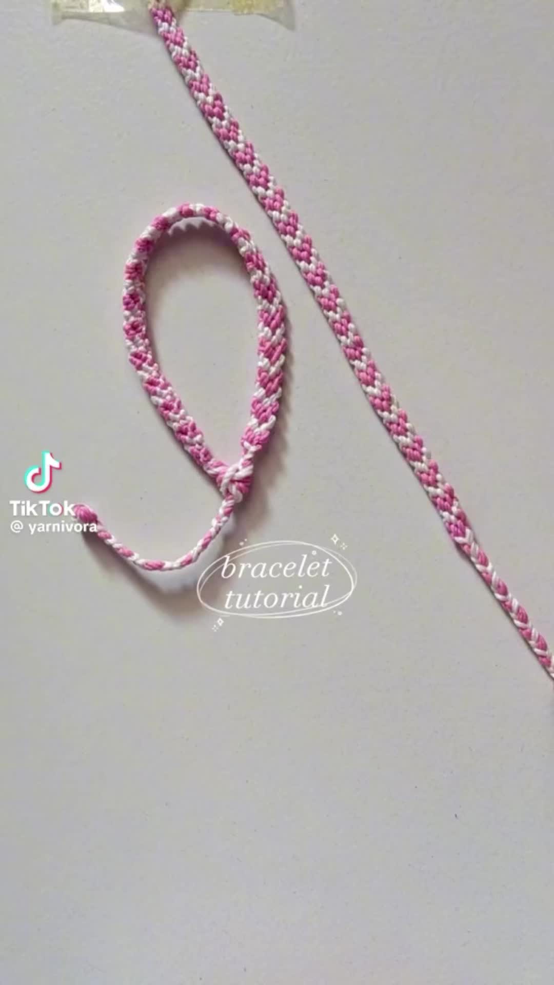 This may contain: a pink and white braided lanyard with a tag on it