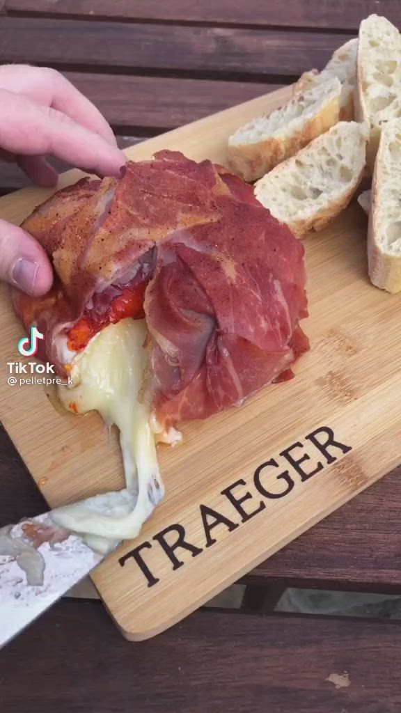 This may contain: someone is cutting up a sandwich on a cutting board that says traegerr