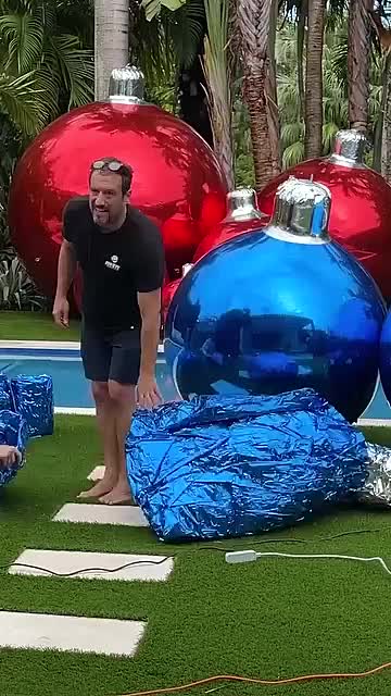 This may contain: two men are standing in front of christmas ornaments on the grass near a swimming pool