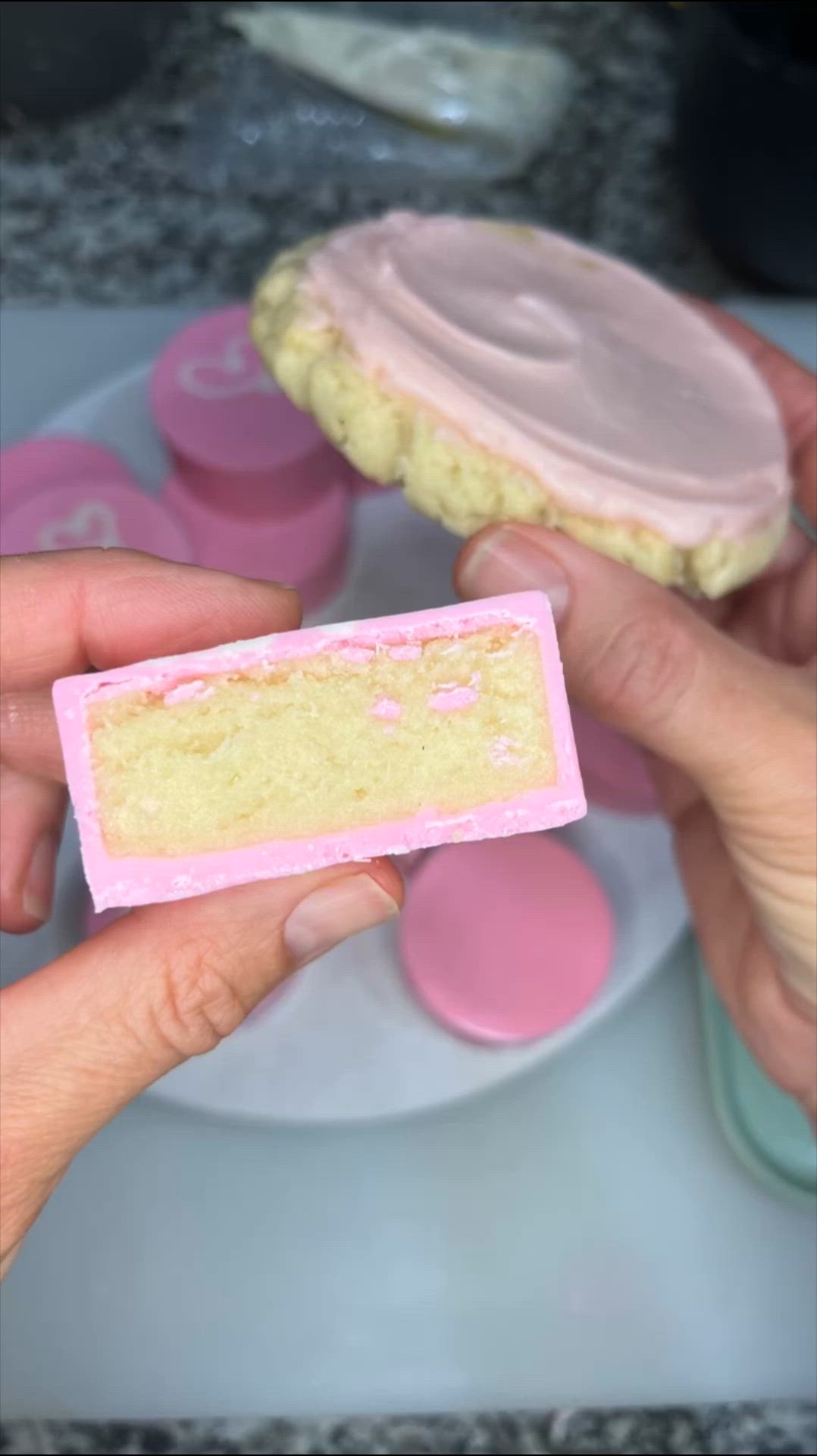 This may contain: a person holding a piece of cake in front of some pink and yellow icing