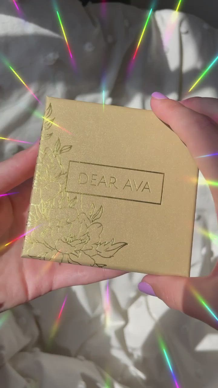 This may contain: a person holding up a box with the word dear ava on it in their hands