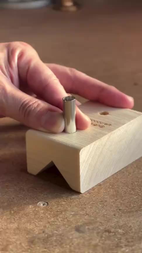 This may contain: a person's hand using a small wooden block to make a piece of wood