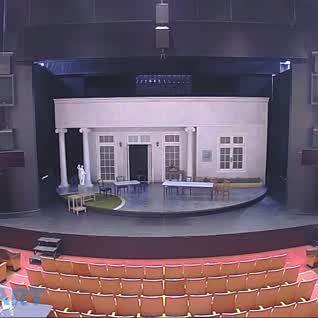 This may contain: an empty stage with chairs and tables in front of the building that is on display