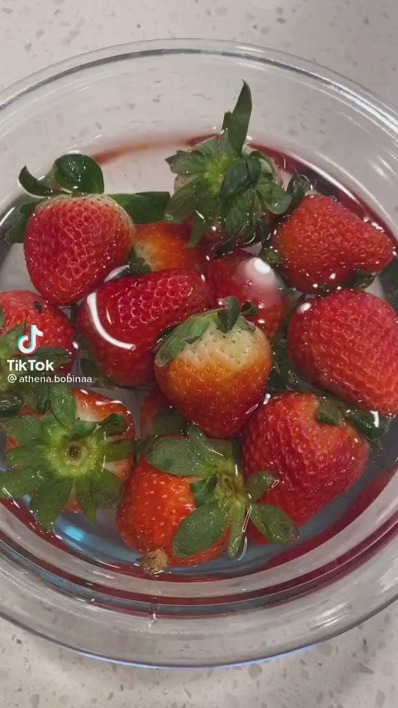 This may contain: some strawberries are sitting in a bowl of water