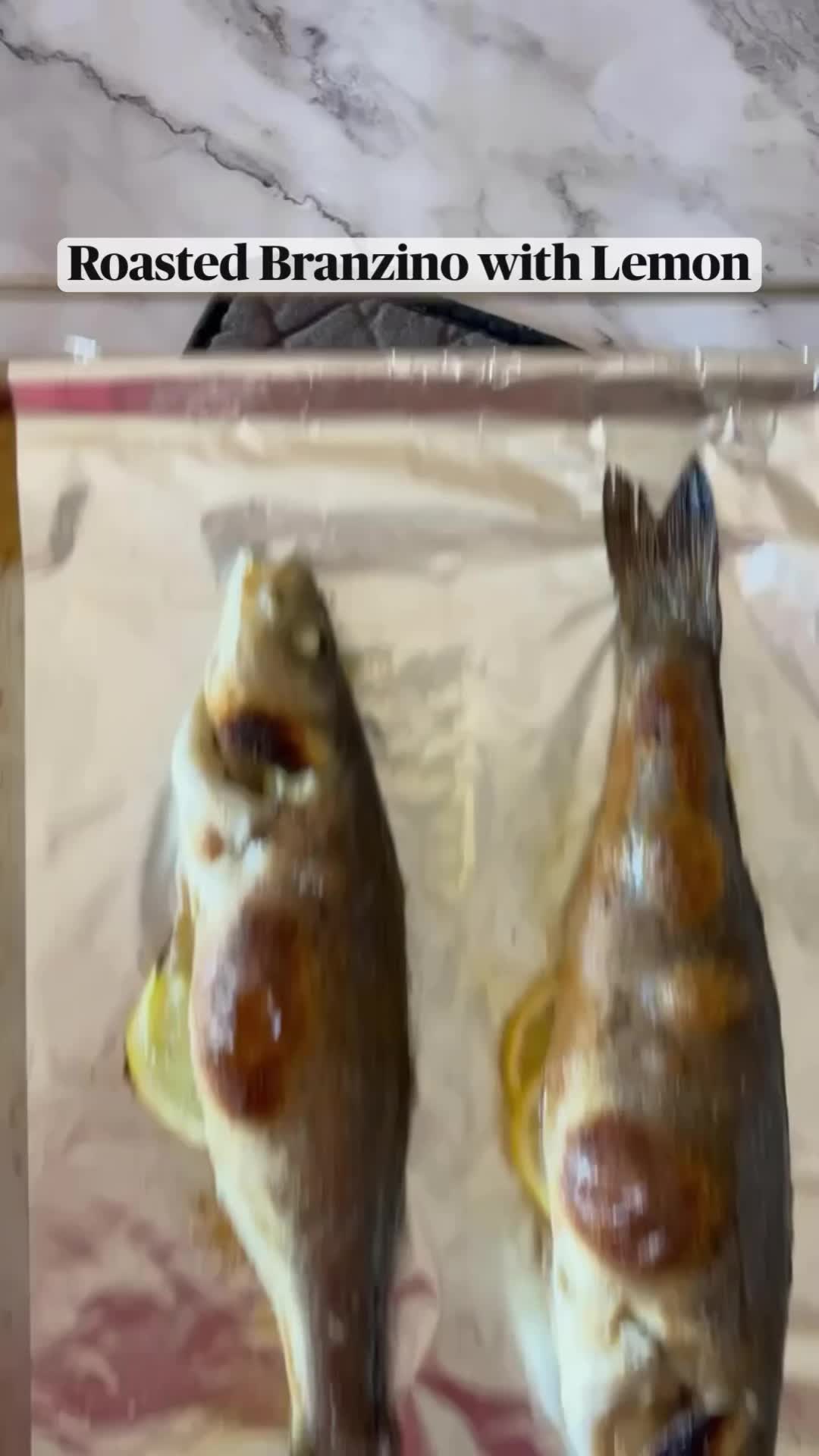 This may contain: two fish on a plate with lemons and parsley