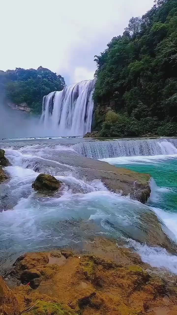 This may contain: the water is rushing over the rocks and into the river to get to the waterfall