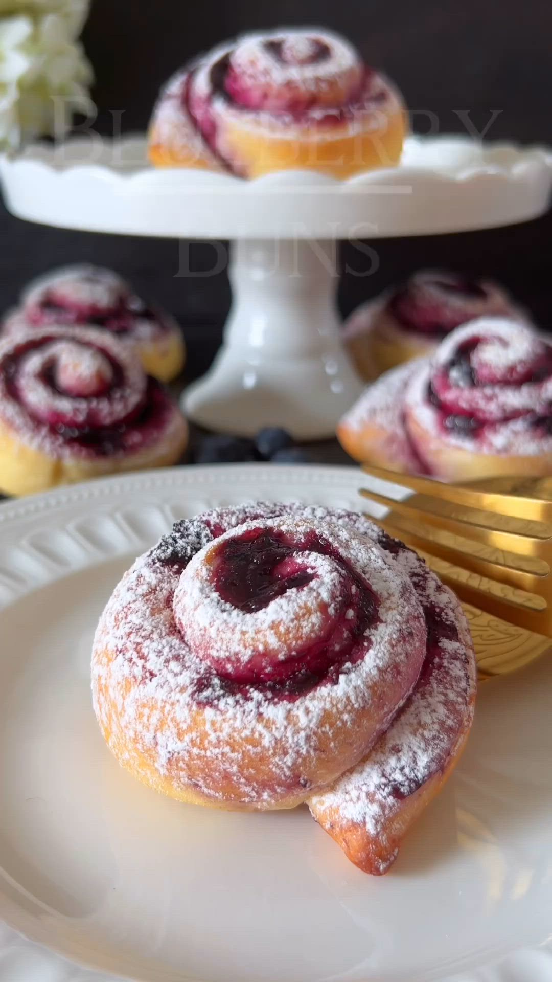 This may contain: blueberry buns on a white plate with powdered sugar sprinkled on top