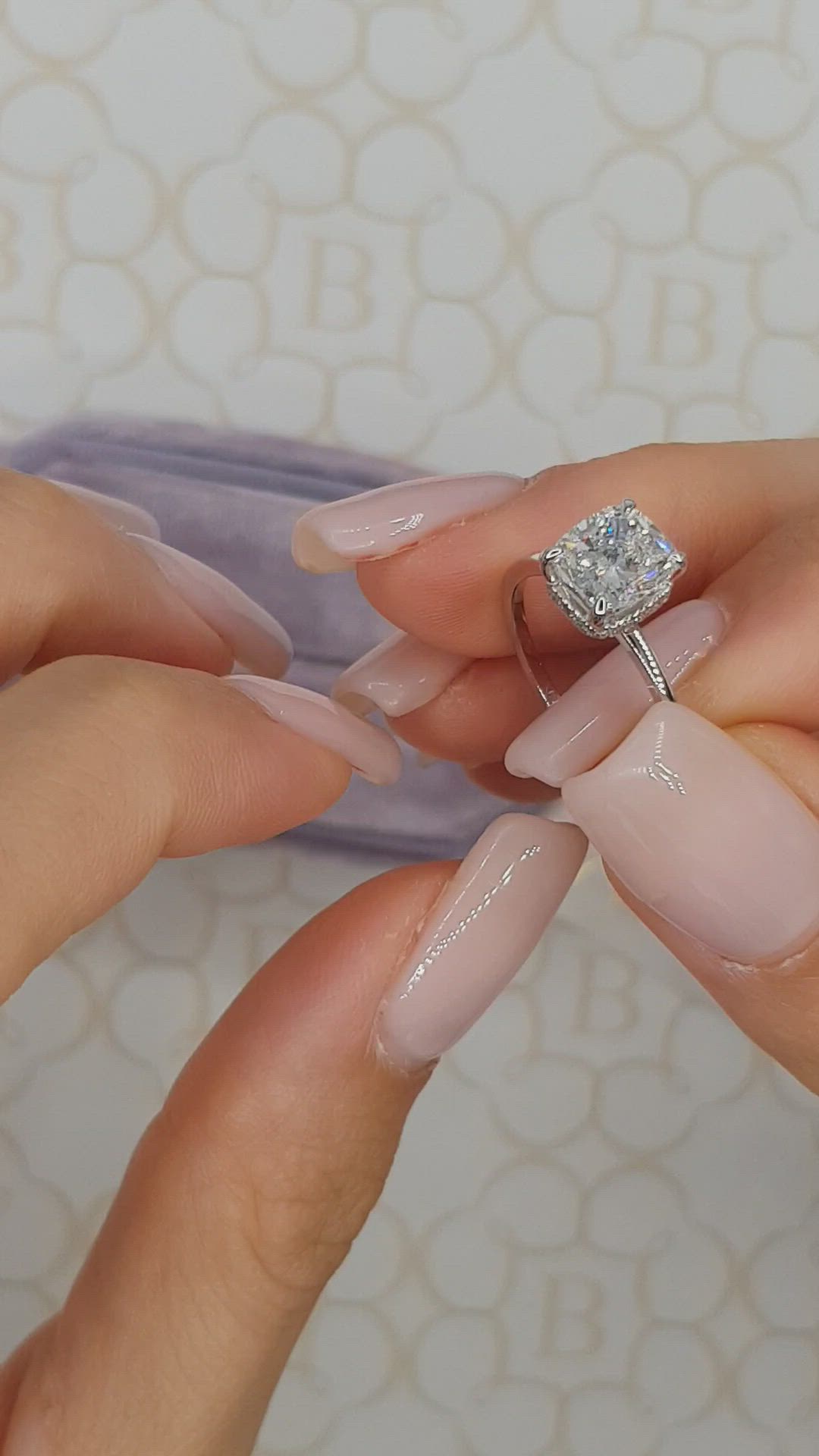 This may contain: two hands holding a diamond ring on top of each other's fingers, with pink and white nail polish