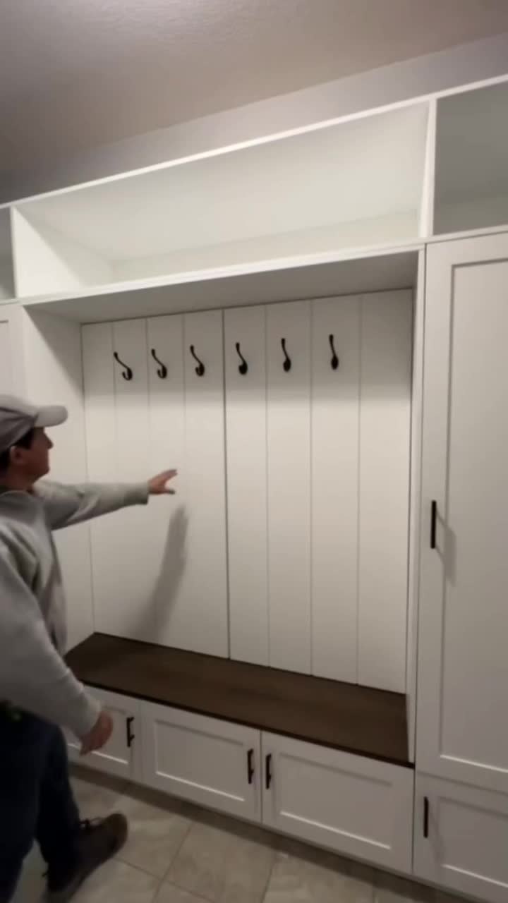 This may contain: a man pointing at some white cabinets in a room