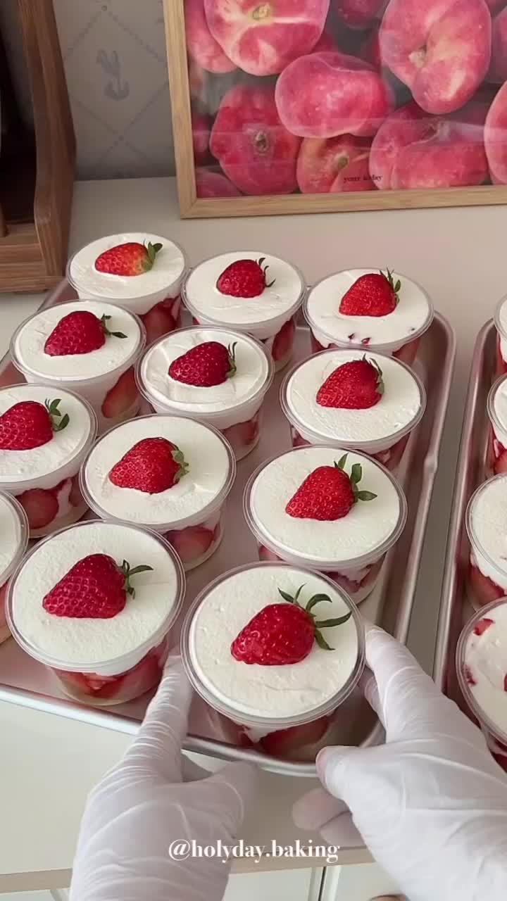 This may contain: someone in white gloves is placing strawberries on top of the cupcake pans